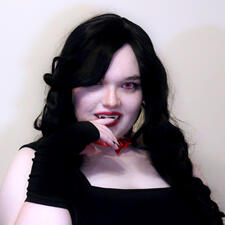 A vampire with long, black curls. She has red eyes (only one of which is visible), red lipstick, and a red, bow choker. She wears a black, square-neck tank top and armwarmers. One hand is up with the index finger hanging in front of her mouth.