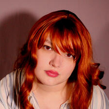 A woman with a neutral expression and red hair. The hair has sideswept bangs and is curled at the ends. She has a glossy pink lip and a blue-and-white retro-styled striped shirt. Her eyes have a detailed painted texture using different shades of red.